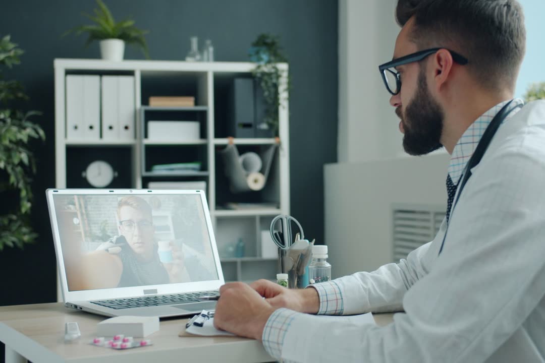 A clinician in a video visit with a patient on a laptop